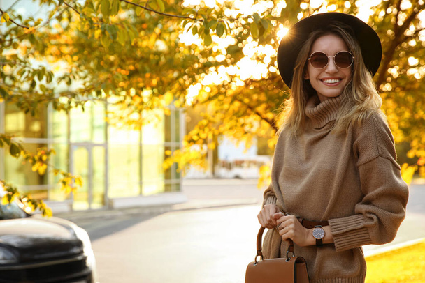 Beautiful young woman wearing stylish sweater in autumn park - Фото, изображение