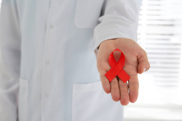 Doctor holding red awareness ribbon, closeup. World Aids day - Fotografie, Obrázek