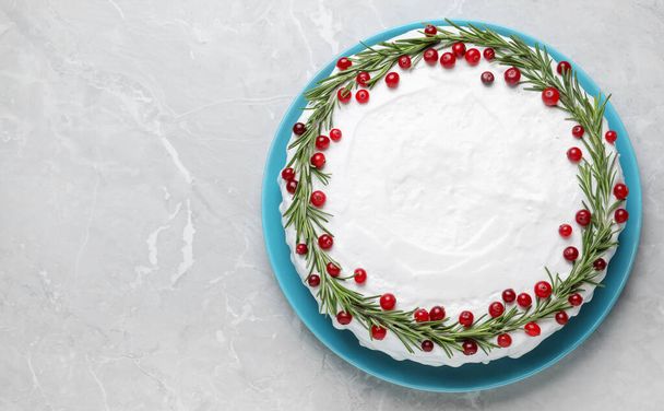 Traditional Christmas cake decorated with rosemary and cranberries on light grey marble table, top view. Space for text - Foto, Bild