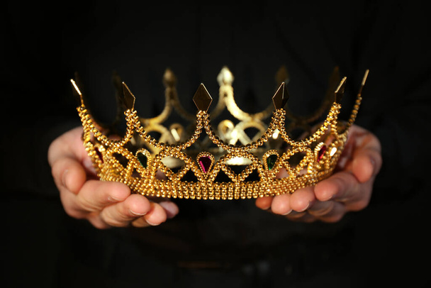 Woman holding beautiful golden crown, closeup. Fantasy item - Фото, изображение
