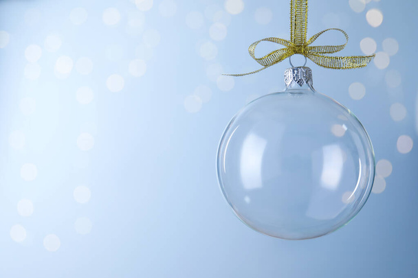 Transparent glass Christmas ball against light background with festive lights. Space for text - Photo, Image