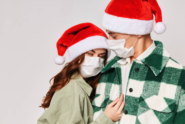 мужчина и женщина в медицинских масках обнимают Новый год крупным планом - Фото, изображение
