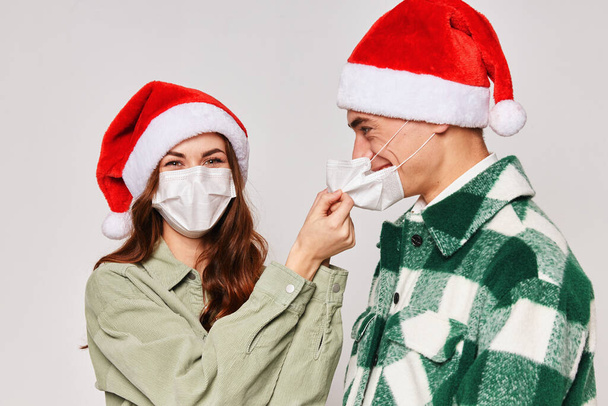 young couple in christmas hats medical masks close-up gray background - Fotó, kép