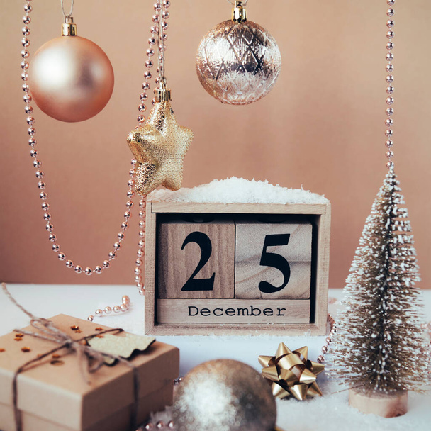 Houten blokkenkalender met 25 december datum, kerstversiering en geschenkdoos op beige achtergrond - Foto, afbeelding