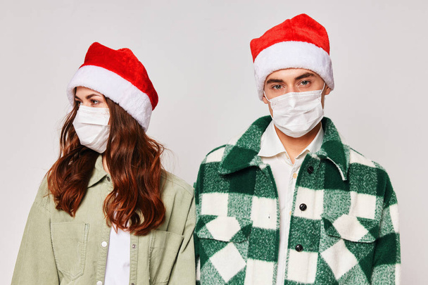 Man en vrouw in medische maskers Nieuwjaar vakantie vriendschap samen - Foto, afbeelding