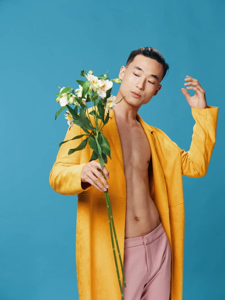 Asian man bukiet białych kwiatów żółty płaszcz niebieski tło Kopiuj przestrzeń - Zdjęcie, obraz
