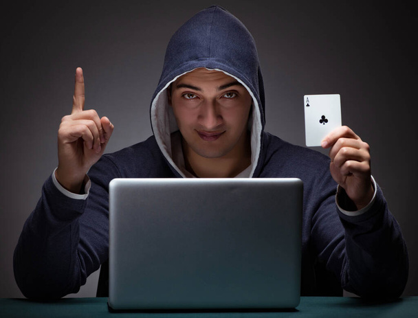 Jeune homme portant un sweat à capuche assis devant un ordinateur portable - Photo, image