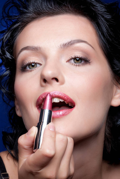 Young beautiful woman applying cosmetics onto her face - Foto, Imagen