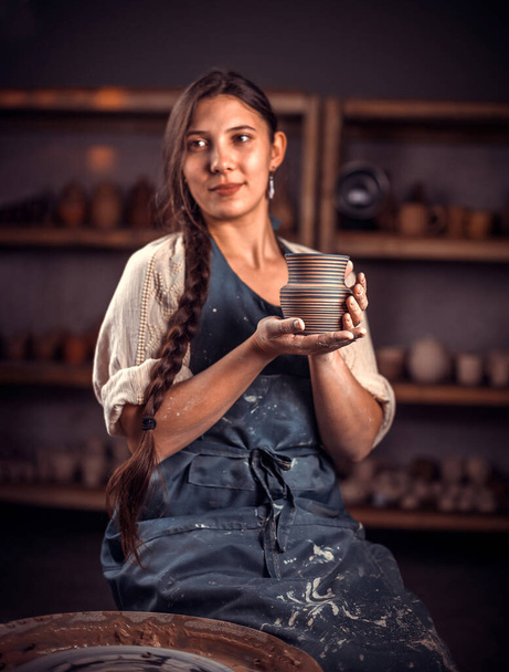 Pottery girl shows the finished clay product in the pottery workshop. Handicraft production. - Zdjęcie, obraz