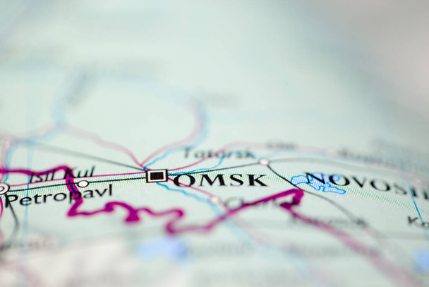 Shallow depth of field focus on geographical map location of Omsk Russia Europe continent on atlas - Photo, Image