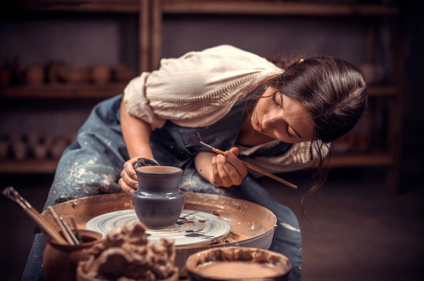 Schöne junge Meisterin demonstriert den Prozess der Herstellung von Keramikgeschirr mit der alten Technik. Volkshandwerk. - Foto, Bild
