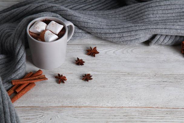 Cup of chocolate with marshmallow, spices, grey knitted scarf on white wooden table background. Winter drink concept. Spicy cocoa, menu, high angle, closeup, copy space - Фото, зображення