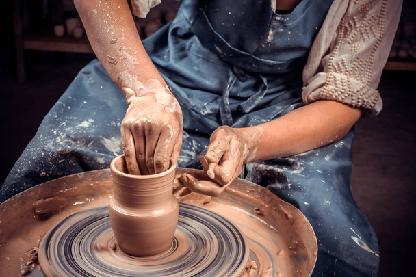 Close-up A woman potter in beautifully sculpts a deep bowl of brown clay and cuts off excess clay on a potters wheel in a beautiful workshop - Photo, Image