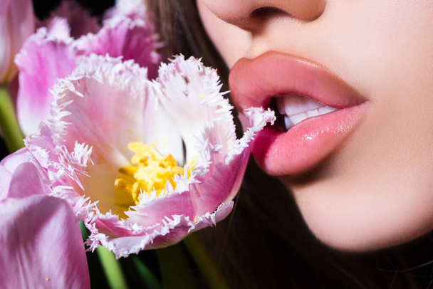 Sexy sensual young woman lips with tulips flowers bouquet. Blowjob and kiss, sensual tongue licks a tulip flower. Sexy female mouth and spring flower. Oral sex, licking. - Фото, изображение