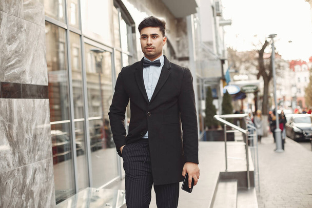 Stylish businessman in a black suit standing outside - 写真・画像