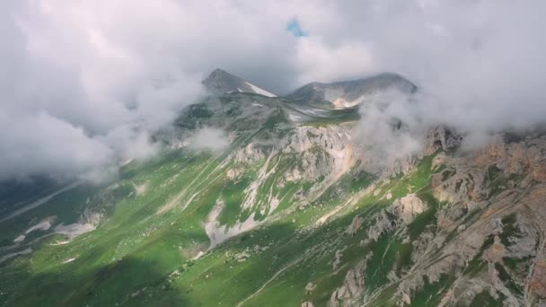 Epische ochtend verbazingwekkende berglandschap onder bewegende grote wolken in de zomer zonnig weer, Adygea, Rusland. Luchtfoto van bergen met sneeuw en gras. Prachtige natuur van de Kaukasus vanaf hoogte. - Video