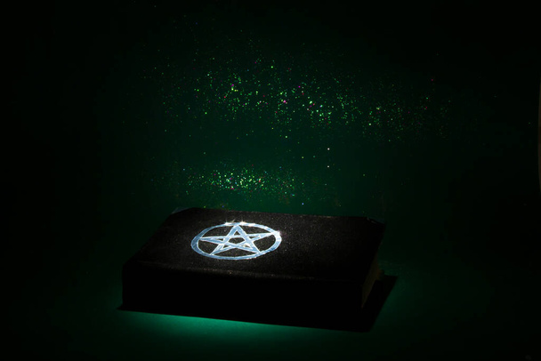 Μαύρο βιβλίο μαγείας στο σκούρο πράσινο φόντο. Όμορφη αποκρυφιστική τελετή. Ευαίσθητη διάθεση. - Φωτογραφία, εικόνα