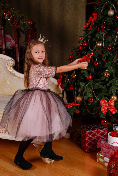 una bambina carina in un vestito che si prepara per il nuovo anno. in attesa della festa, la piccola principessa è pronta per la celebrazione. - Foto, immagini