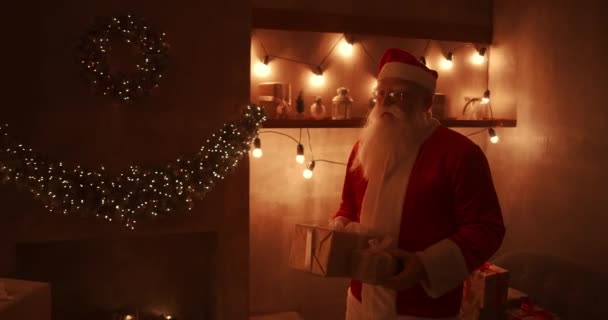 In der Weihnachtsnacht bringt der Weihnachtsmann Geschenke nach Hause, während alle schlafen. Weihnachtsmann legt Geschenke unter dem Weihnachtsbaum im geschmückten Haus ab - Filmmaterial, Video