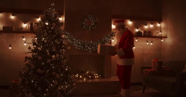 Papai Noel traz presentes sob a árvore de Natal para as crianças. Dê presentes a crianças na noite de Natal. Papai Noel coloca um presente sob a árvore de Natal - Filmagem, Vídeo