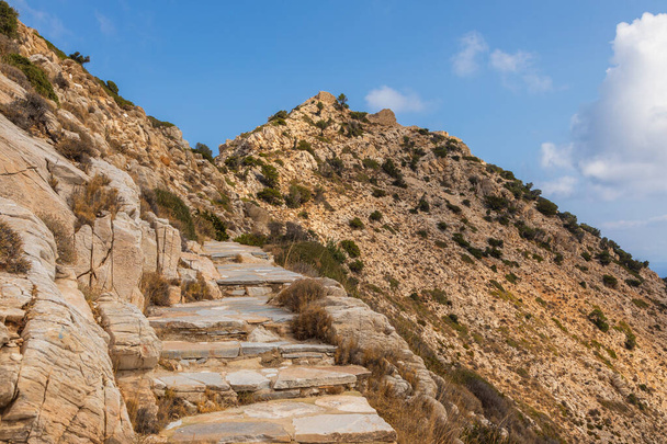Camino de piedra de montaña a Palaiokastro, ruinas castillo bizantino en la cima de la colina. Isla de Ios, Grecia. - Foto, imagen