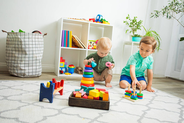 Children playing with wooden toys sitting on a floor - Φωτογραφία, εικόνα