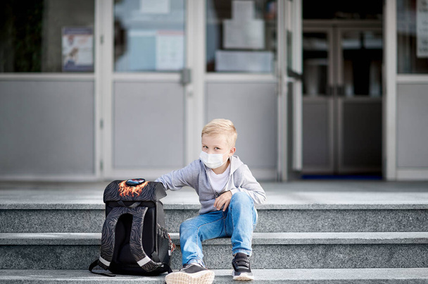 Enfant avec masque facial posé sur les marches de l'école - Photo, image