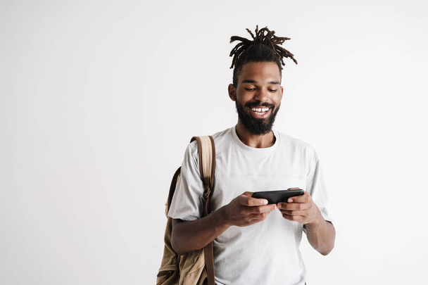 Foto von fröhlichen afrikanisch-amerikanischen Kerl spielen Online-Spiel auf dem Handy isoliert über weißem Hintergrund - Foto, Bild