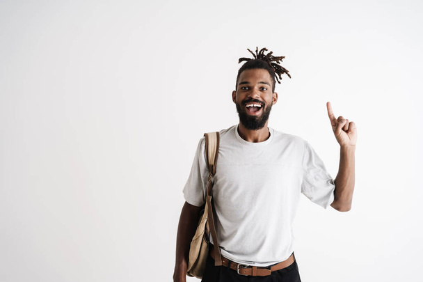 Photo of excited african american guy smiling while pointing finger upward isolated over white background - 写真・画像