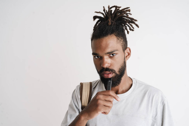 Photo of unshaven african american guy smoking electronic cigarette isolated over white background - Fotografie, Obrázek