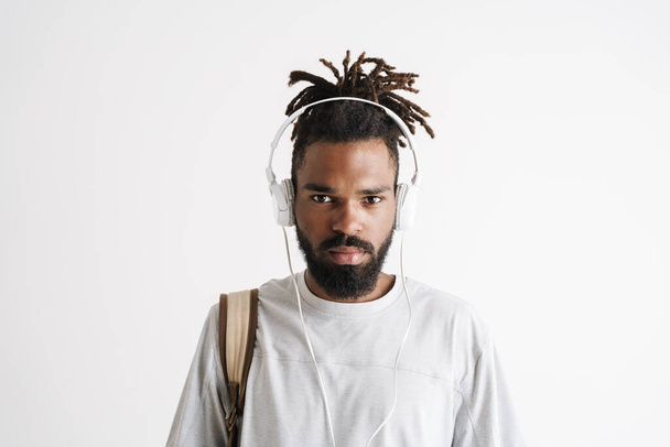 Fotografie vážný africký Američan chlap poslech hudby s sluchátky izolované přes bílé pozadí - Fotografie, Obrázek