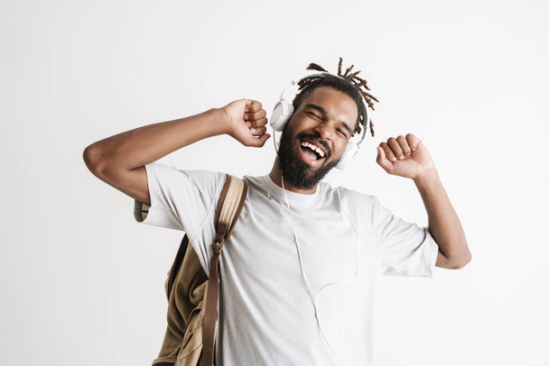 Photo of happy african american guy listening music with headphones and singing isolated over white background - Photo, image