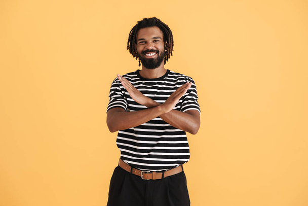 Photo of cheerful african american guy showing stop gesture isolated over yellow background - Foto, Imagem