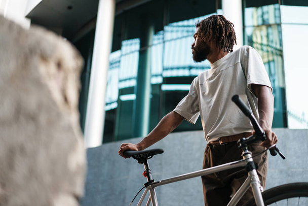 Handsome african american guy posing with bicycle at city street - Foto, Bild