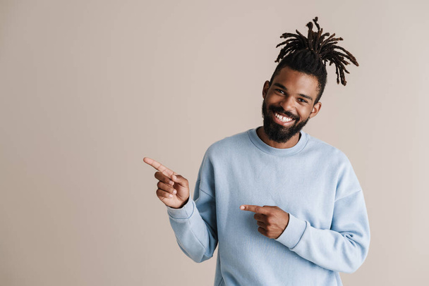 Joyful african american guy smiling and pointing fingers aside isolated over white background - Foto, afbeelding