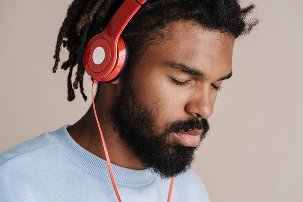 Focused african american guy listening music with headphones isolated over white background - Foto, Imagem