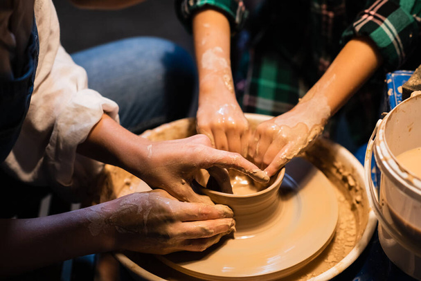 o processo de modelar pratos de barro em uma roda Potters, as mãos de uma jovem e uma criança. - Foto, Imagem