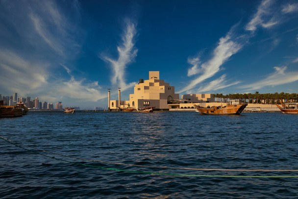 Μουσείο Ισλαμικής Τέχνης, Ντόχα, Κατάρ στο φως της ημέρας εξωτερική άποψη με αραβικό κόλπο και dhow στο προσκήνιο και σύννεφα στον ουρανό στο παρασκήνιο - Φωτογραφία, εικόνα