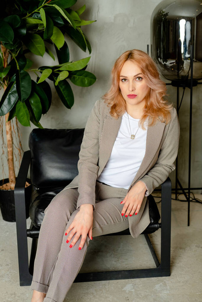 woman sitting on a chair. portrait of a strong businesswoman. The girl in a classic suit in the office. Girl in a loft style office - Foto, immagini