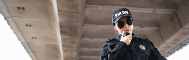 portret van politievrouw in zonnebril in gesprek op radio op straat, banner - Foto, afbeelding