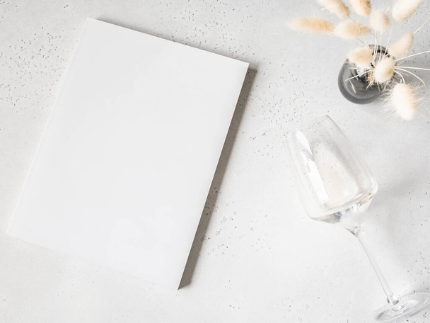 Couverture de magazine blanc maquette, lagurus blanc dans un vase et verre de vin blanc sur fond gris clair. vue de dessus. Espace de copie - Photo, image