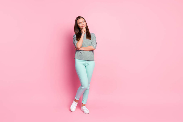 Full size photo of thinkable sweet girl stand look empty space wear blue pants sneakers shirt isolated on pink color background - Valokuva, kuva