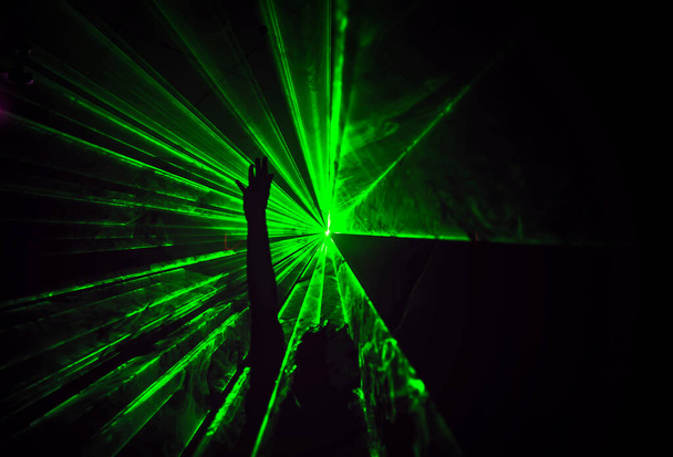 Trippy obraz nocy z ludźmi tańczącymi na zewnątrz w festiwalu muzyki leśnej z wiązkami laserowymi w tle. - Zdjęcie, obraz