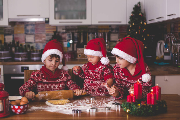 Sweet toddler child and his older brother, boys, helping mommy preparing Christmas cookies at home in kitchen - Photo, Image