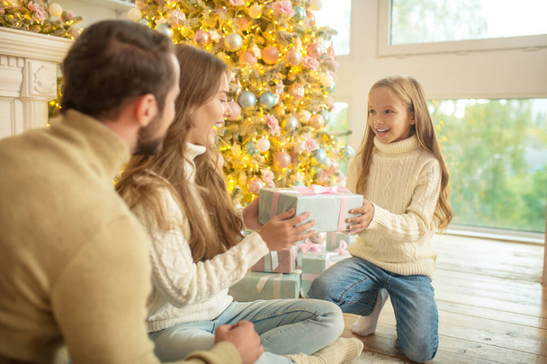 Young family sitting near christmas tree and feeling happy - 写真・画像