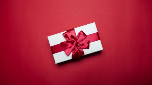 Біла подарункова коробка обертається на барвистому фоні. Червоний, зелений, фіолетовий і синій кольори
. - Кадри, відео