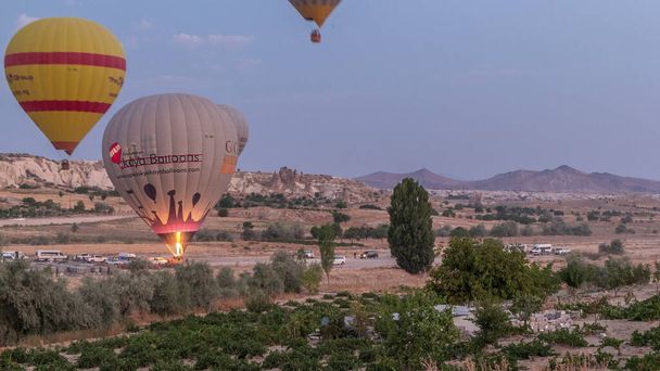 Beautiful colorful hot air balloons take off and flying in clear morning sky above unusual rocky landscape timelapse in Cappadocia, Turkey - Foto, afbeelding