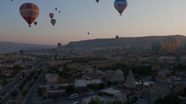 Aerial view from hot air balloon with other flying balloons during Sunrise over the fairytale landscape hills of Kapadokya with morning light. Goreme, Cappadocia, Turkey - Fotó, kép