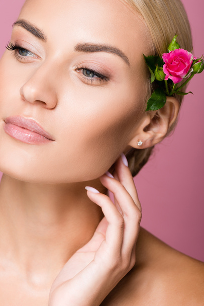 beautiful blonde woman with perfect skin and rose flower in hair isolated on pink - Photo, Image