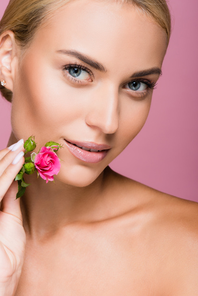 όμορφη ξανθιά γυναίκα με τέλειο δέρμα και τριαντάφυλλο λουλούδι απομονωμένο σε ροζ - Φωτογραφία, εικόνα